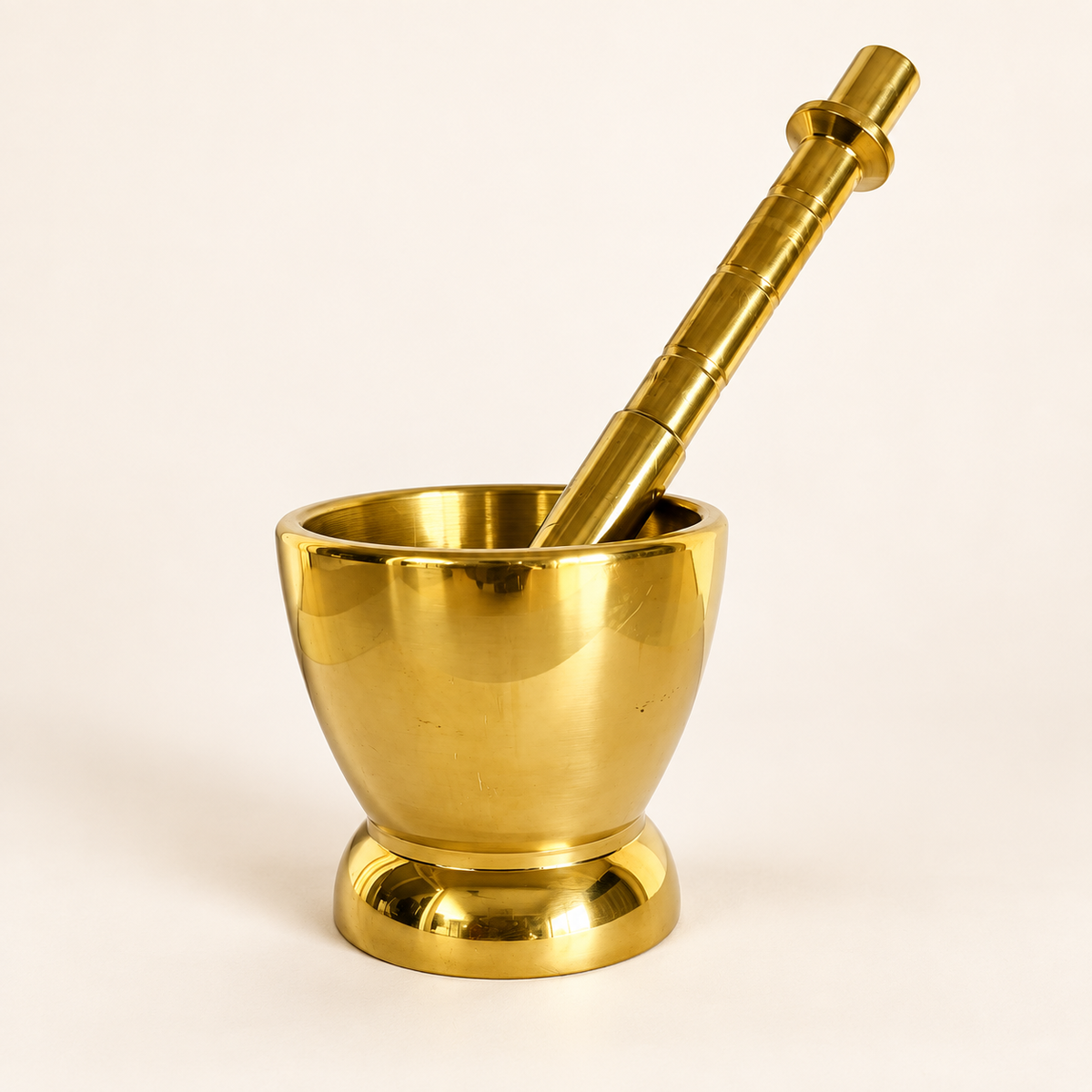 Brass mortar and pestle on a warm ivory background